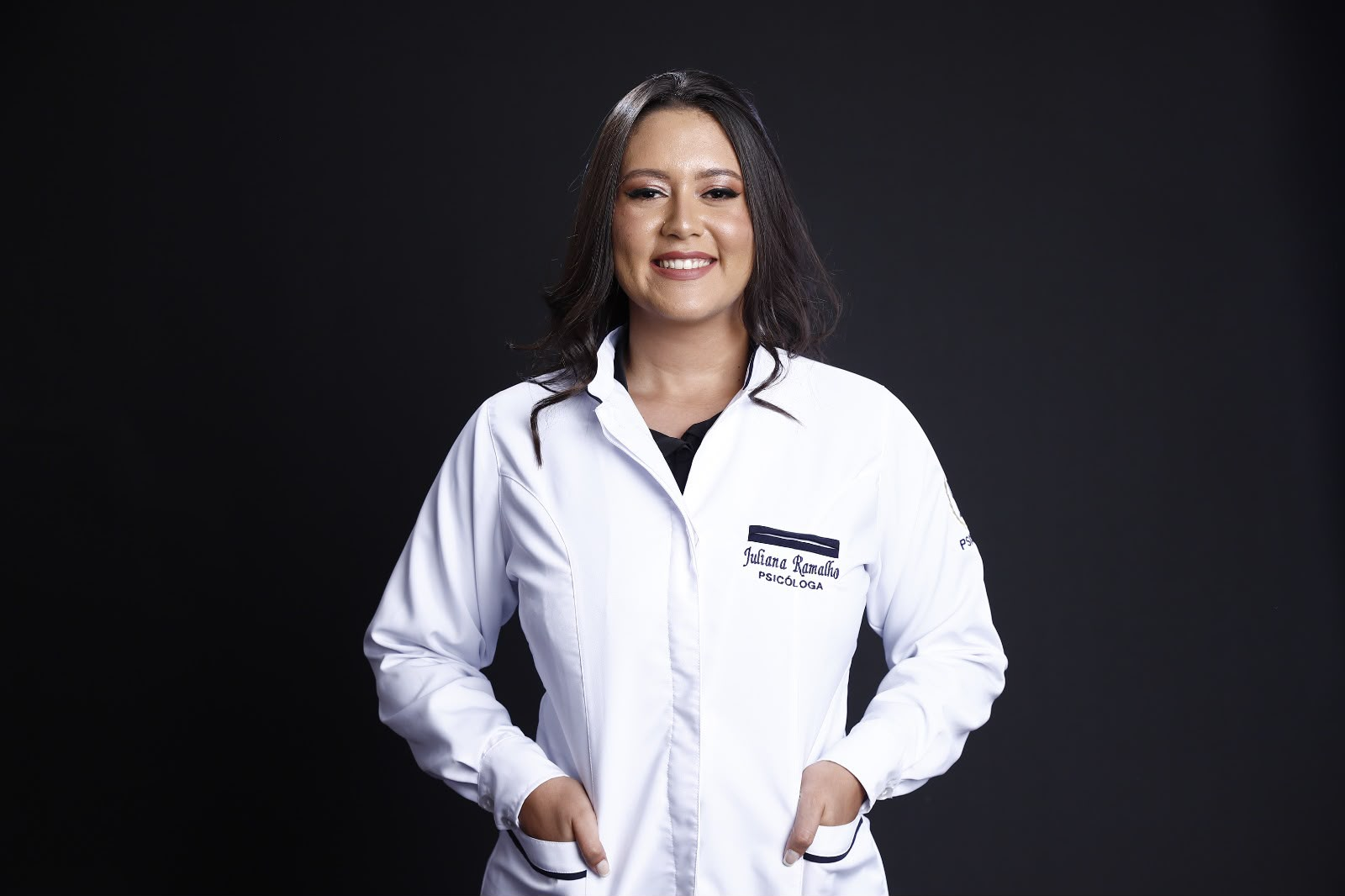 Juliana Ramalho, psicóloga, sorrindo, de jaleco branco